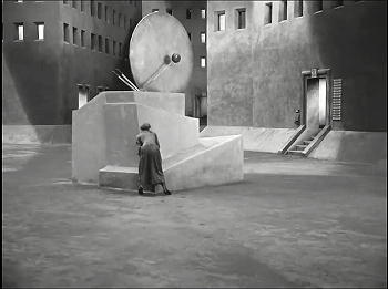 『メトロポリス』 1927、約1時間55分：集合住宅間の広場とモニュメント風チャイム